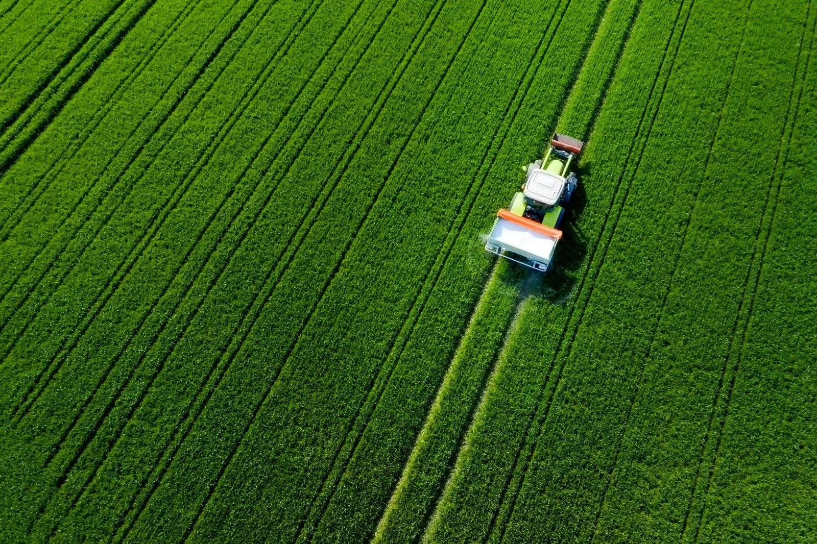 Aerial view of tractor spraying green farmland